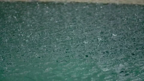 Tropical rain drops falling onto the surface of a swimming pool. Slow motion Stock Footage 224212748