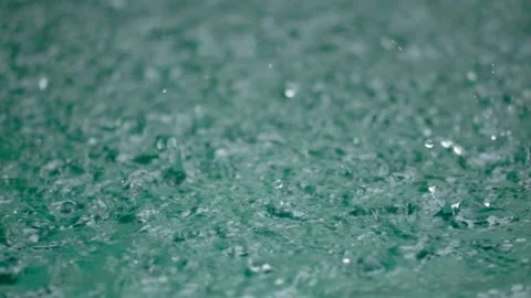 Tropical rain drops falling onto the surface of a swimming pool. Slow motion Stock Footage 224212852