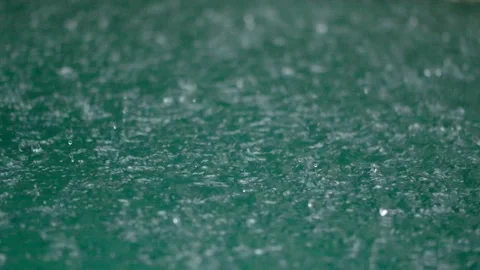 Tropical rain drops falling onto the surface of a swimming pool. Slow motion Vidéo 224212925