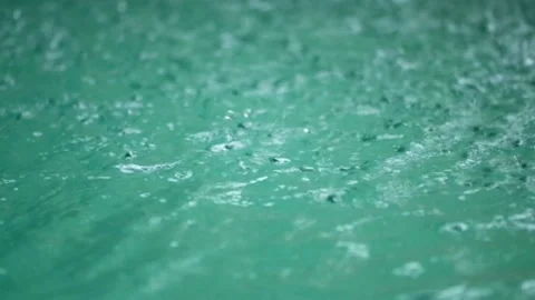 Tropical rain drops falling onto the surface of a swimming pool Stock Footage 228056840
