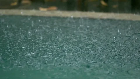 Tropical rain drops falling onto the surface of a swimming pool. Slow motion Stock Footage 228057208