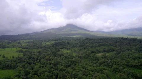 Tropical rainforest leads toward cloud-covered Arenal Volcano in Costa Rica Vídeo Stock 345631501
