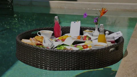 Tropical resort breakfast served on floating tray in pool, featuring Stock Footage 282199211