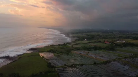 Tropical scenario drone footage of a sunset over ocean and green field Stock Footage 143453953