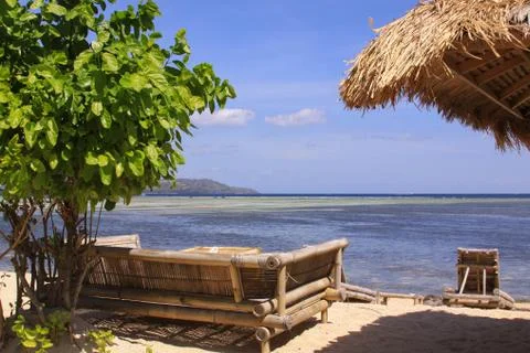 Tropical straw umbrella and sofas at beach bar Stock Photos