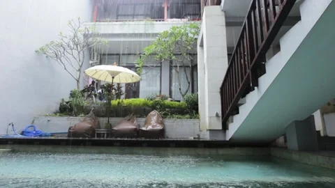 Tropical summer rain falling big rain drops falling down on swimming pool Stock Footage 131394179