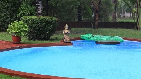 Tropical summer rain falling drops on swimming pool in Thailand Stock Footage 76923685