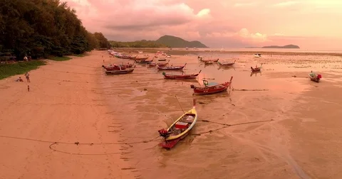 Tropical sunset colors. Drone flying under boats on the shore at low tide Video stock 74901253