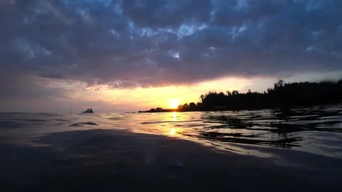 Tropical sunset reflecting on calm ocean surface with boats Video stock 311713633