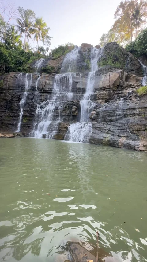 Tropical Waterfall Cascading Down Rocky Tiers, Natural Pool, Upward Pan, Vertica Stock Footage 324770316
