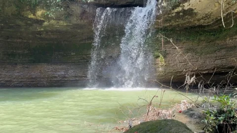 Tropical Waterfall Cascading into Green Pool, Revealing Shot Video stock 325303932