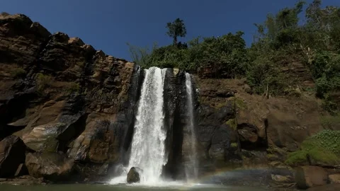 Tropical Waterfall Flowing, Creating Rainbow in Rocky Pool, Low Angle Tilt Down Stock Footage 324771844