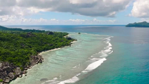 Tropical waves hitting the beach with dense foliage. Seychelles, La Digue. Stock Footage 307566105