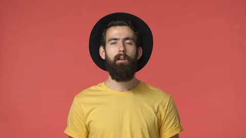 Troubled intense middle-eastern male with beard, black hat and yellow t-shirt Stock Footage 115780947