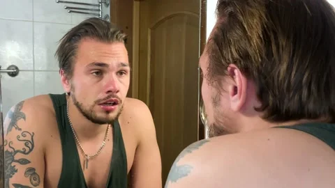 Troubled man staring deeply into the mirror and seeking answers within himself Vidéo 194176326