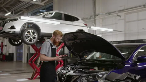 Troubleshooting in car using a tablet and a master mechanic.Car repair station Stock Footage 253390270