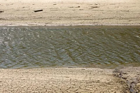 A trough of drying rivers surrounded by dry, cracked mud Stock Photos
