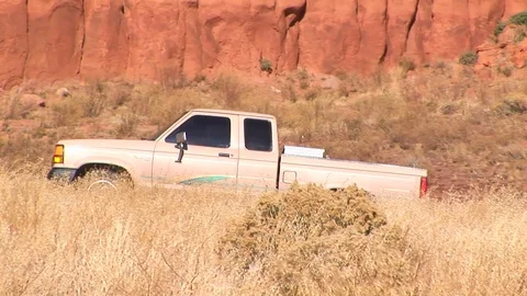 Truck backing down slope at base of Wingate Cliffs in New Mexico USA Stock Footage 103551400