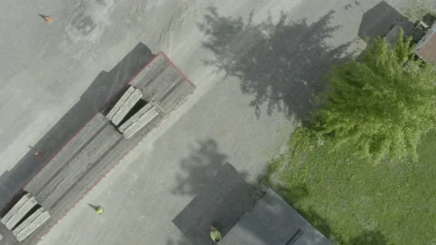 Truck driver backing a flatbed trailer across a gravel lot drone overhead Stock Footage 137498469
