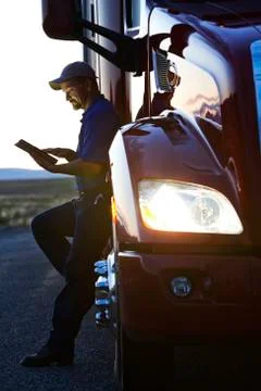 Truck driver checking his notebook computer log while standing next to the cab Stock Photos