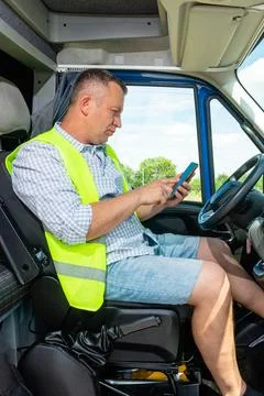 Truck driver checking smartphone inside the cabin Fotos de archivo