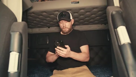 Truck driver resting and using smartphone in sleeper cab Stock-Footage 346970050