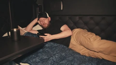 Truck driver resting and using smartphone in sleeper cab Vidéo 346970590