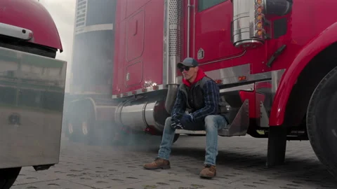 Truck Driver Rests Between Two Large Trucks in a Busy Lot Stock Footage 319908647