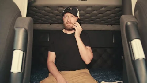 Truck driver talking on the phone inside sleeper cabin 库存影片 346970163