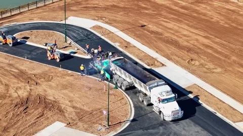Truck dumping hot bitumen into the container of a road paving machine Stock Footage 279355164