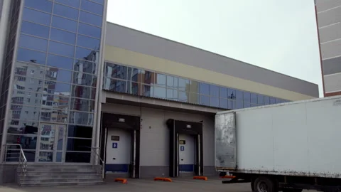Truck moves reverse to closed doors of warehouse building Stock Footage 240491953