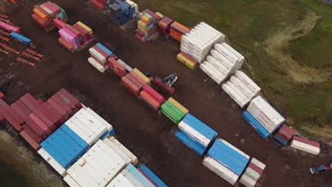 Truck offloading on Shipping Container yard with reach stacker Circling aerial Stock Footage 345520057