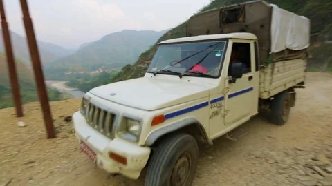 Truck passing through a rocky road with green lush mountains surrounding it Stock Footage 77444553