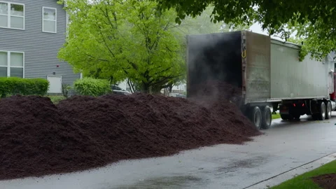 Truck unloading large pile of fresh mulch in residential neighborhood for Stock Footage 335959017