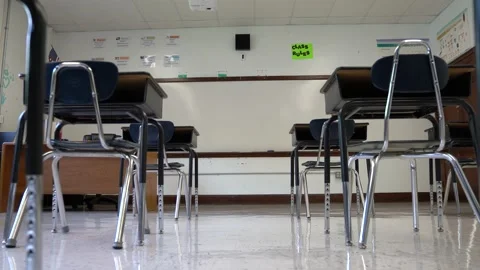Trucking motion push in showing empty school classroom with chairs under desks Stock Footage 138961566
