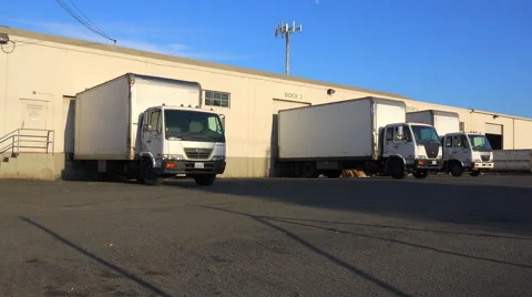 Trucks are lined up at a commercial warehouse and shipping facility. Stock Footage