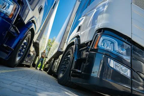 Trucks Parked Side by Side in a Freight Yard Under a Clear Daytime Sky Stock Photos
