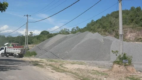 Trucks pass a stack of gravel at the open mining area Stock Footage 233196380