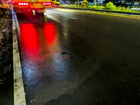 Truck's red tail light reflects on wet road 库存照片