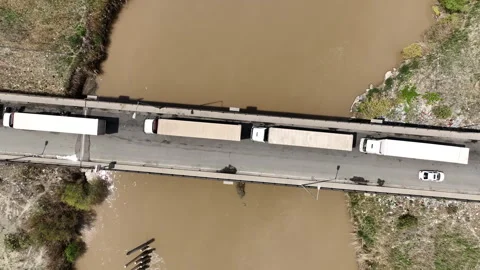 Trucks stand on a bridge with a river flowing under it Stock Footage 260484330