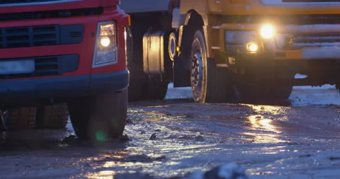 Trucks with their headlights on are driving on a muddy road Stock Footage 147628141