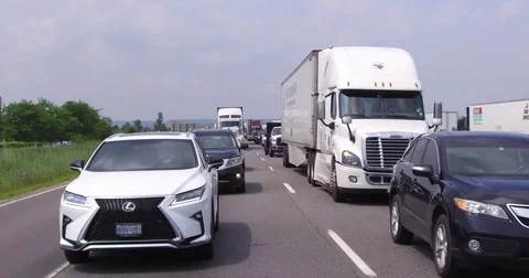 Trucks tractor trailers and cars driving on busy highway Stock Footage