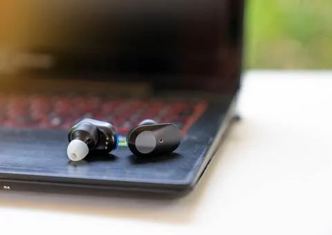 True Wireless Earbuds Basic on laptop relax in front house. Stock Photos