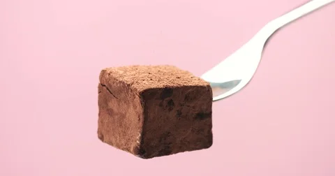 Truffle cube on a fork and cacao powder falling on it Stock Footage 77255368
