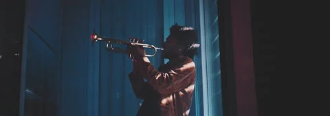 A trumpeter playing in a dark room with rays of light filtering through the Stock Footage 202309774