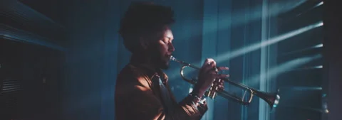 Trumpeter playing in a room with rays of light filtering through the shutters Stock Footage 202310992