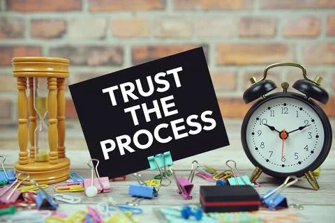 Trust The Process text on paper card with hourglass and stationary on woode.. Foto stock