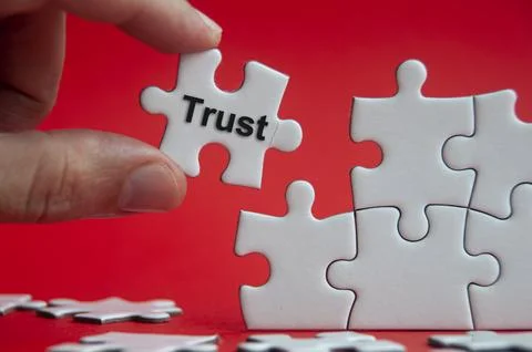 Trust text on jigsaw puzzle with red background - Working relationship and .. Stock Photos