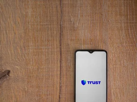 Trust Wallet app launch screen on smartphone on wooden background Stock Photos