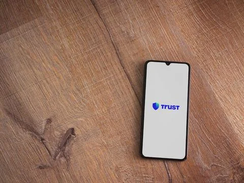 Trust Wallet app launch screen on smartphone on wooden background Stock Photos